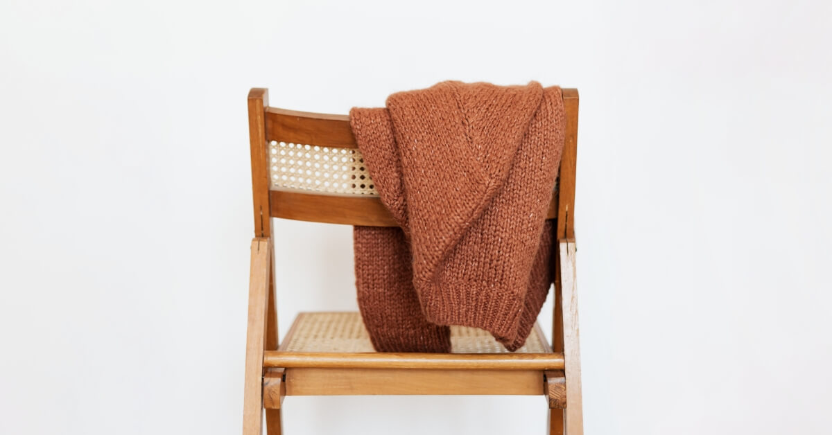 <img src="moda-na-jesień-2022.jpg"alt="Jesienny sweter przewieszony przez oparcie krzesła">